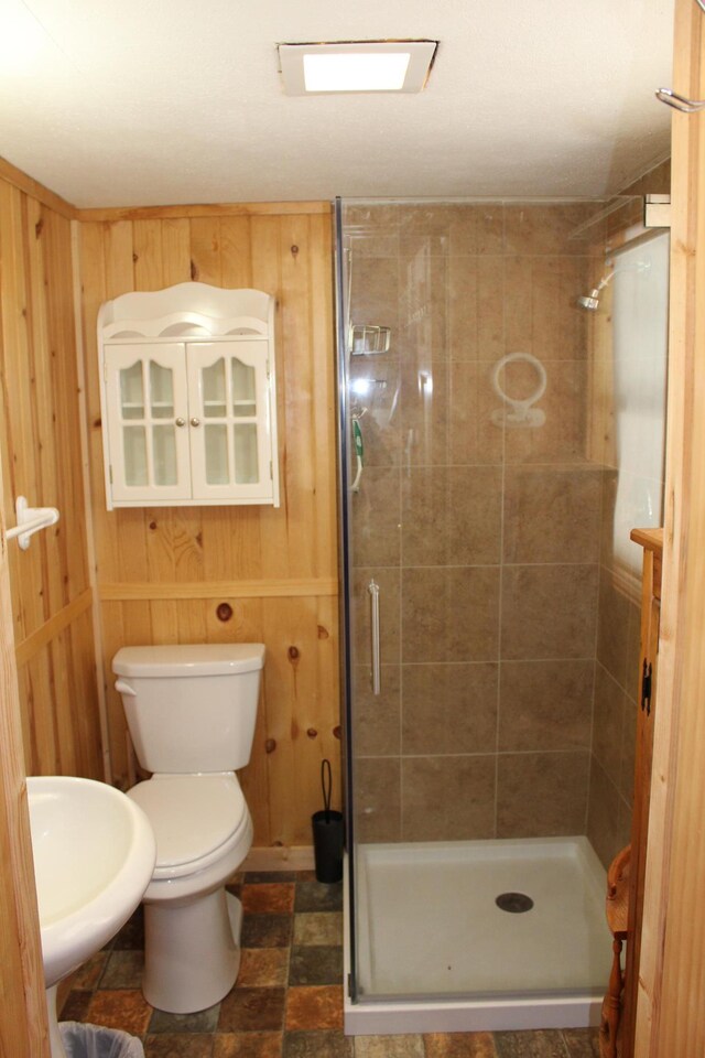 bathroom featuring toilet, a stall shower, and wood walls