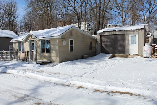 view of snowy exterior with a detached garage and an outdoor structure