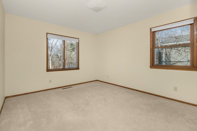 unfurnished room featuring baseboards, visible vents, and light colored carpet