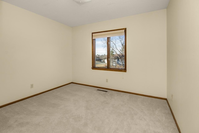 unfurnished room with baseboards, visible vents, and light colored carpet