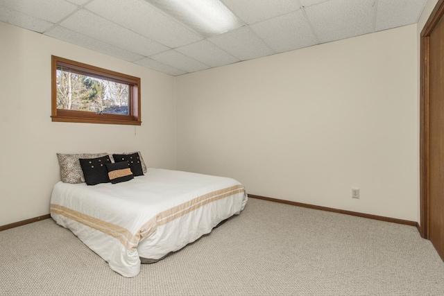 bedroom with carpet floors, baseboards, and a drop ceiling