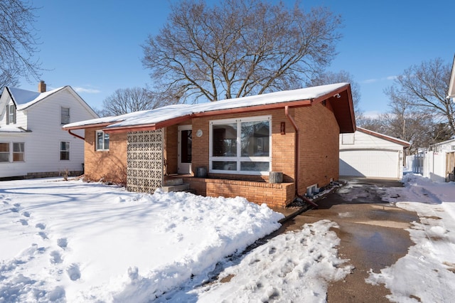 view of front of house featuring a detached garage, brick siding, and an outdoor structure