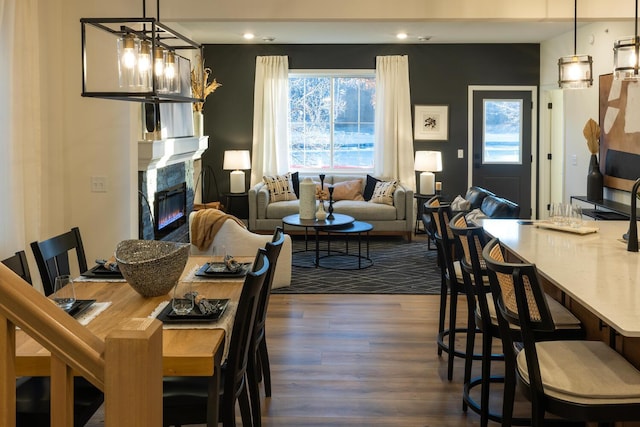 dining area with a high end fireplace, a notable chandelier, recessed lighting, and wood finished floors