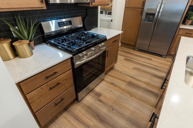 kitchen featuring stainless steel appliances, brown cabinets, light countertops, and separate washer and dryer