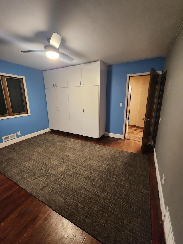 unfurnished bedroom featuring a ceiling fan, dark wood finished floors, visible vents, and baseboards