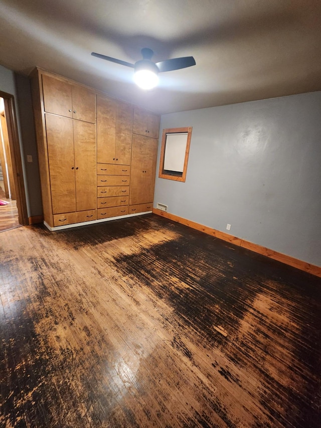 unfurnished bedroom with visible vents, baseboards, dark wood finished floors, and a ceiling fan