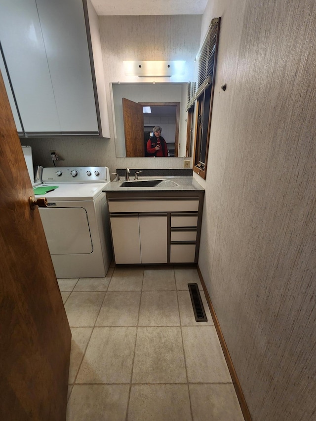 washroom with light tile patterned floors, cabinet space, visible vents, a sink, and washer / dryer