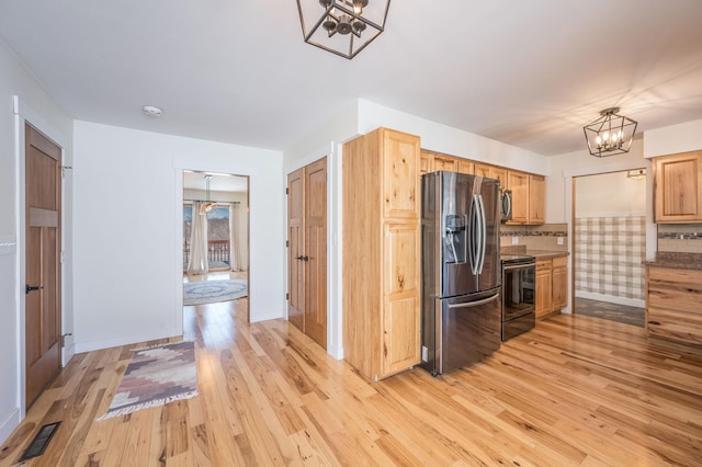 kitchen with light wood finished floors, baseboards, visible vents, stainless steel appliances, and a chandelier