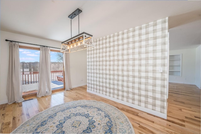 dining room featuring built in features, baseboards, and wood finished floors