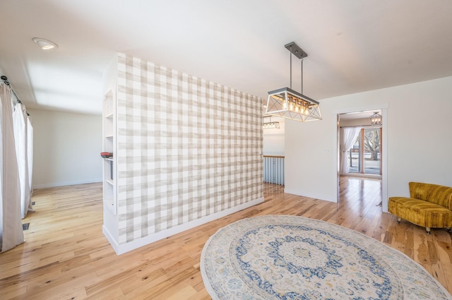 dining area with light wood-style floors, an accent wall, baseboards, and wallpapered walls