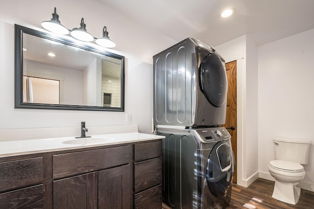 bathroom featuring recessed lighting, toilet, vanity, stacked washing maching and dryer, and wood finished floors