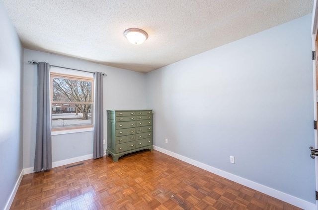 spare room featuring visible vents, baseboards, and a textured ceiling