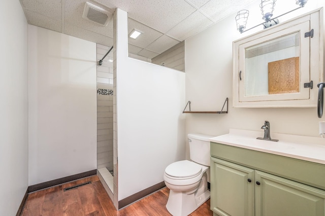 full bathroom featuring toilet, wood finished floors, vanity, visible vents, and a tile shower