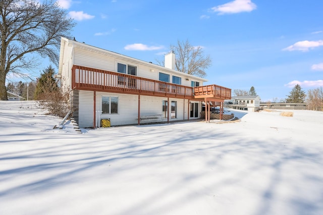 snow covered house featuring a chimney and a deck