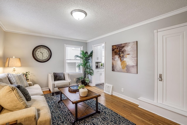 living area with a textured ceiling, ornamental molding, wood finished floors, and baseboards