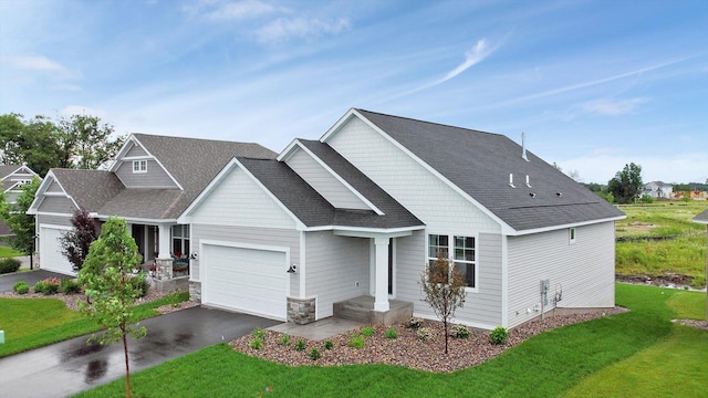 craftsman-style house featuring a garage, stone siding, aphalt driveway, and a front yard