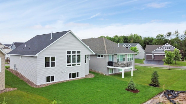 back of property featuring a shingled roof and a yard