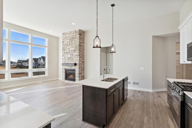 kitchen featuring stainless steel appliances, light countertops, hanging light fixtures, a sink, and dark brown cabinetry