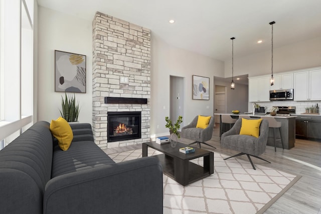 living area featuring light wood-type flooring, recessed lighting, and a stone fireplace