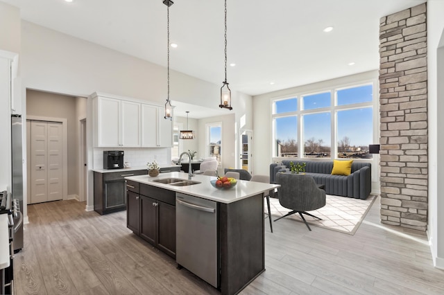 kitchen with a kitchen island with sink, light countertops, dishwasher, and a sink