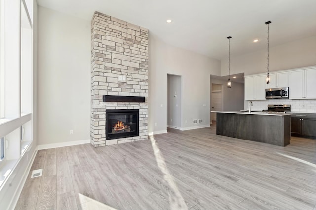 kitchen with pendant lighting, light countertops, appliances with stainless steel finishes, open floor plan, and white cabinetry