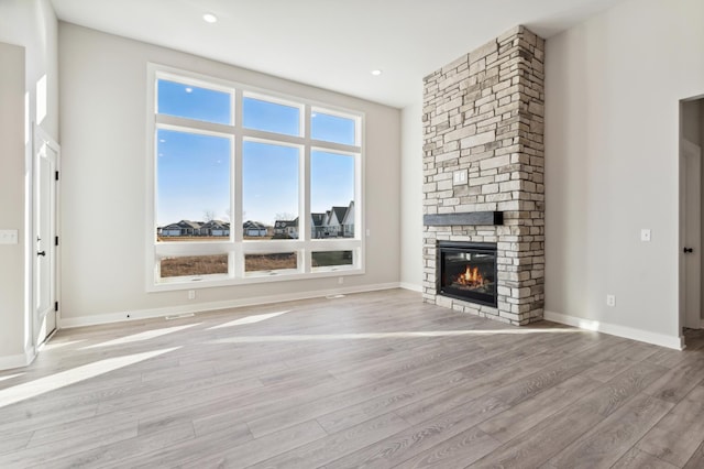 unfurnished living room featuring recessed lighting, baseboards, a fireplace, and light wood finished floors