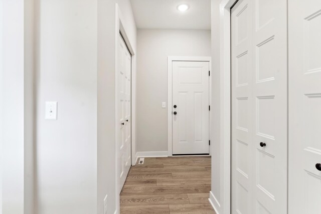 hall with light wood-style flooring and baseboards