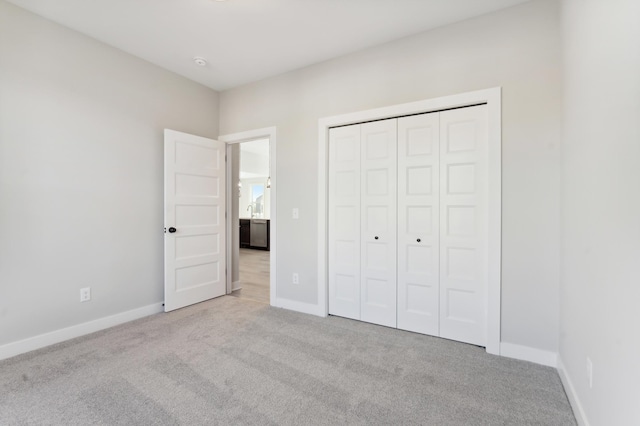 unfurnished bedroom featuring light carpet, baseboards, and a closet