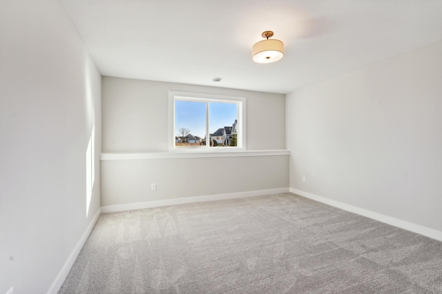 unfurnished room featuring light colored carpet and baseboards