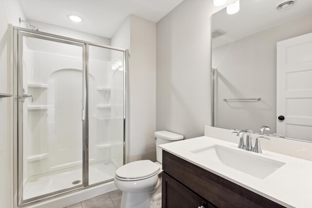 bathroom featuring tile patterned flooring, toilet, vanity, visible vents, and a stall shower