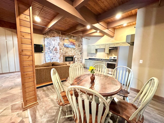 dining area featuring wood ceiling, a fireplace, light wood finished floors, and beam ceiling