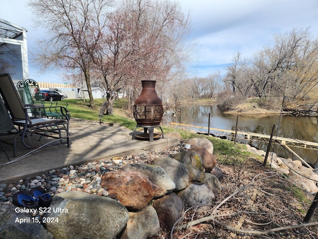 view of yard with a patio area, a water view, and a fire pit