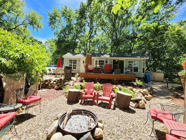 back of house with a trampoline, an outdoor fire pit, and a deck