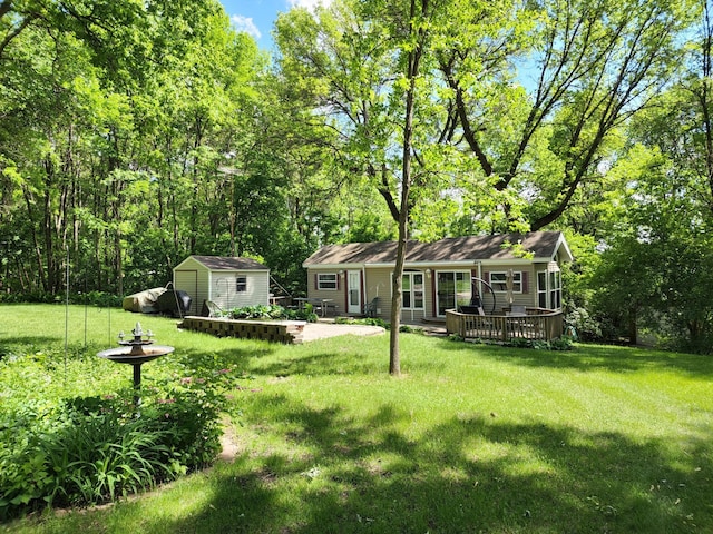 view of yard featuring a patio, a storage unit, an outdoor structure, and a wooden deck