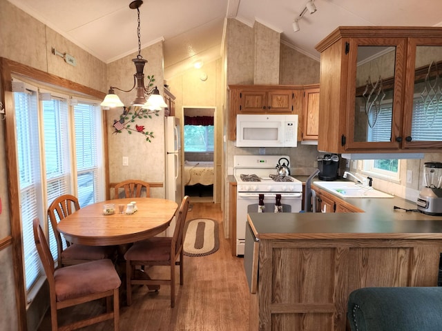 kitchen with white appliances, light wood finished floors, vaulted ceiling, crown molding, and a sink