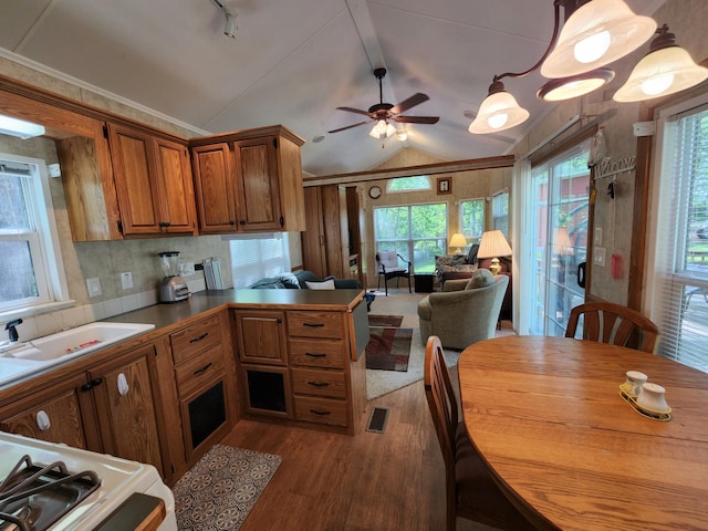 kitchen featuring lofted ceiling, backsplash, brown cabinetry, dark wood-type flooring, and a peninsula