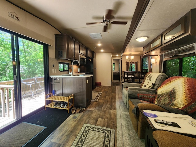 living room with dark wood-style flooring, visible vents, and ceiling fan