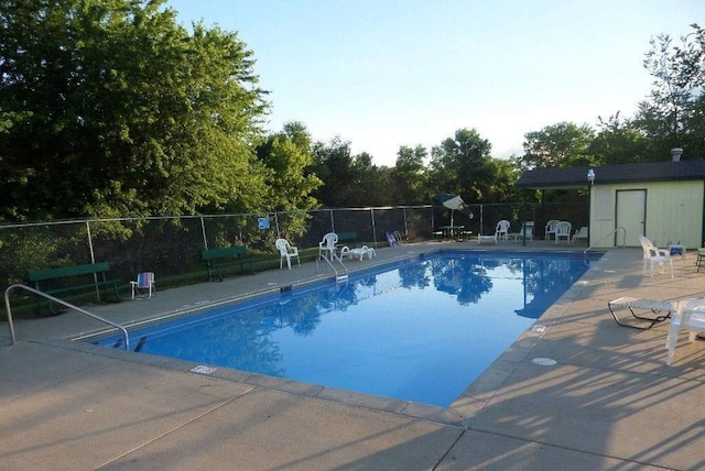 pool featuring fence, an outdoor structure, and a patio