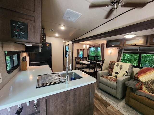 kitchen with dark wood-style flooring, a sink, visible vents, dark brown cabinets, and light countertops