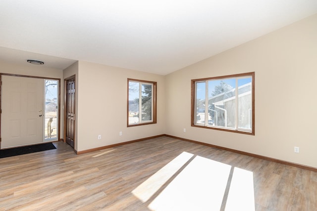 entrance foyer featuring lofted ceiling, light wood-style flooring, and baseboards