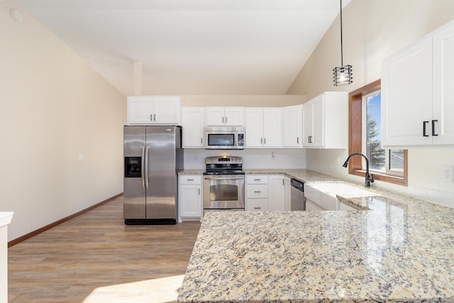 kitchen with tasteful backsplash, decorative light fixtures, stainless steel appliances, white cabinetry, and a sink