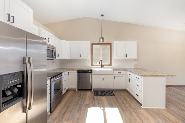 kitchen with hanging light fixtures, appliances with stainless steel finishes, white cabinets, and a sink