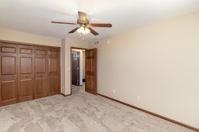 unfurnished bedroom featuring a closet, light colored carpet, visible vents, a ceiling fan, and baseboards