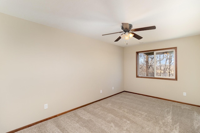 carpeted empty room featuring baseboards and a ceiling fan