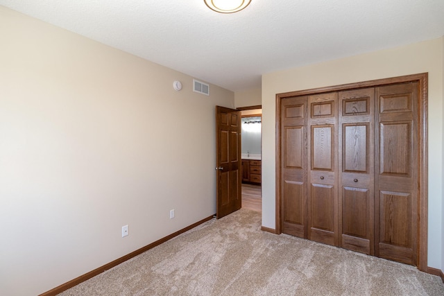 unfurnished bedroom with light colored carpet, a closet, visible vents, and baseboards