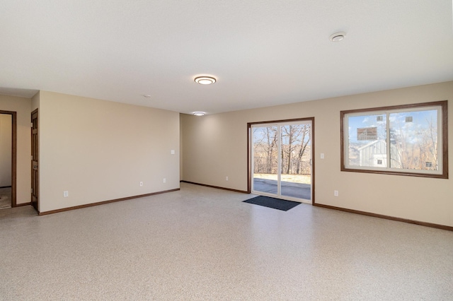 unfurnished room featuring baseboards and light speckled floor