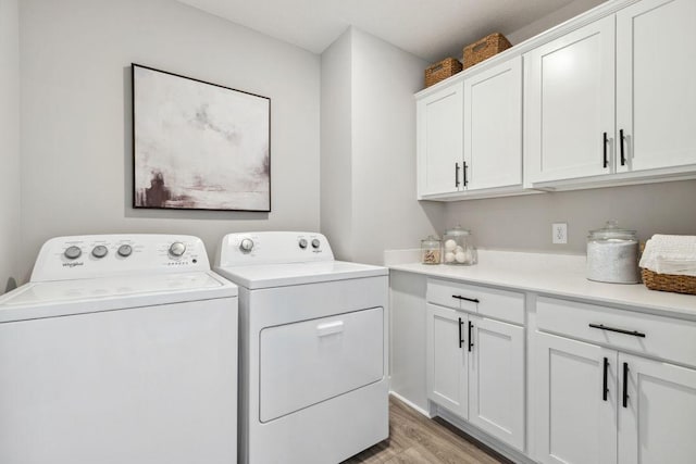 washroom with washing machine and clothes dryer, cabinet space, and light wood-style flooring