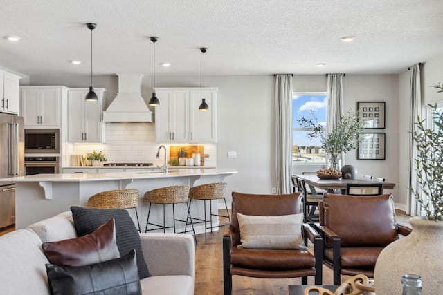 kitchen with premium range hood, built in microwave, stainless steel oven, and light countertops