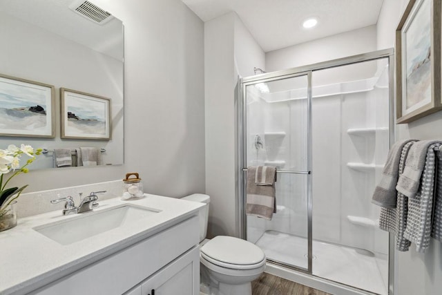 bathroom featuring vanity, wood finished floors, visible vents, a shower stall, and toilet