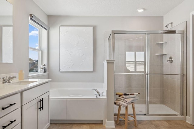 bathroom featuring a garden tub, vanity, a shower stall, and a textured ceiling